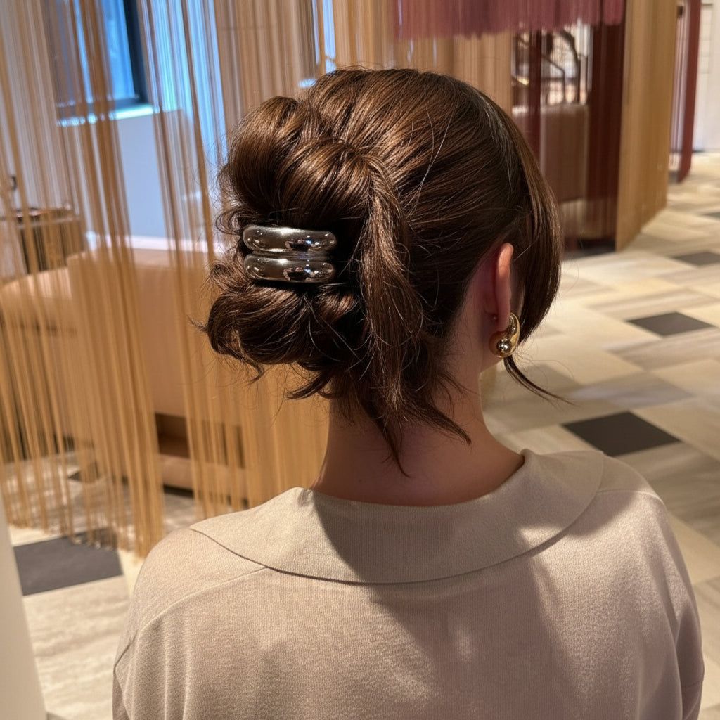 Person with a stylish hair bun wearing a silver hair clip in an indoor setting.